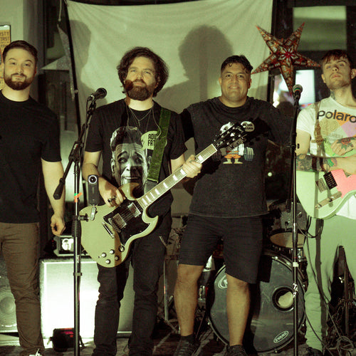 Image shows Adios Faso - a new ONE on Stage band. Four people stand facing camera. Two are holding guitars.
