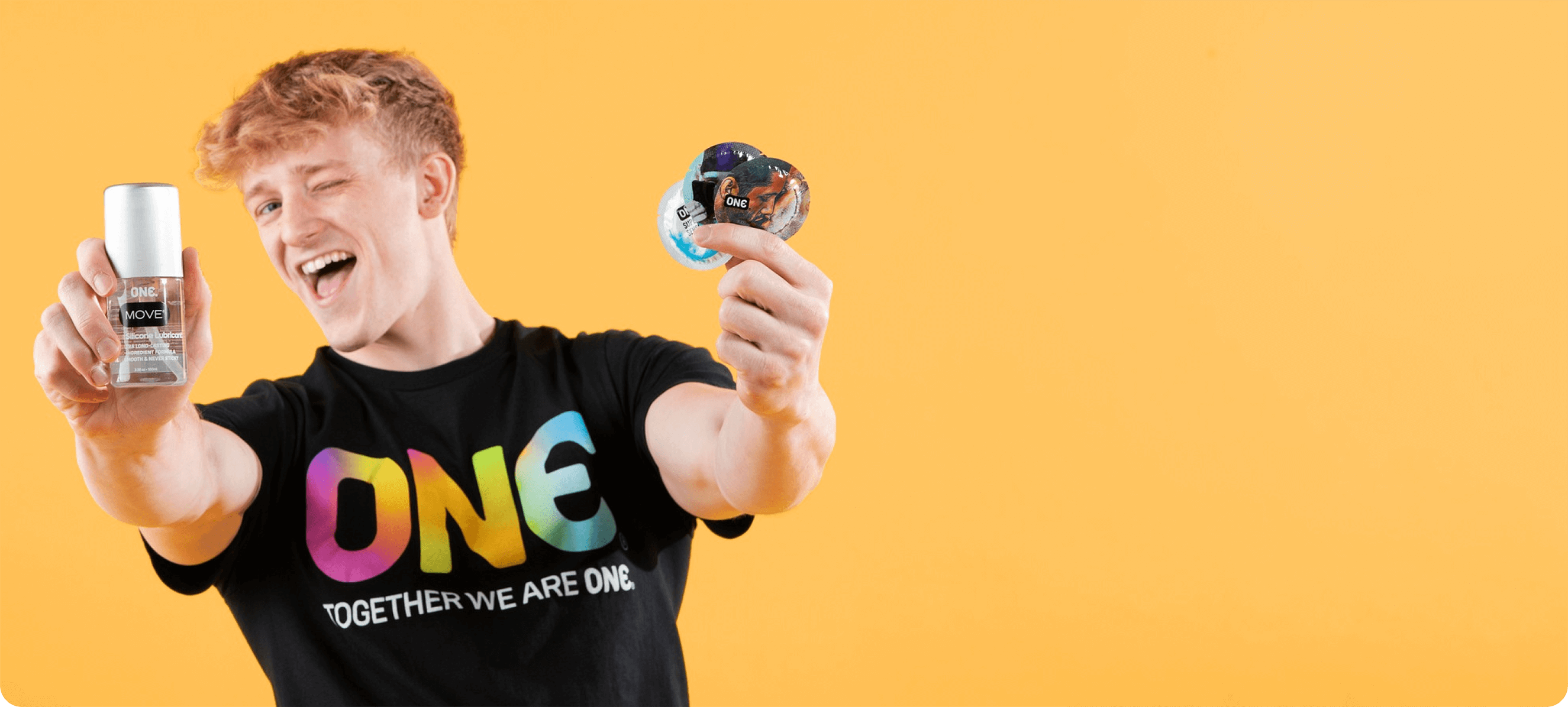 Person wearing a 'ONE' t-shirt with colorful text, holding two small containers against a yellow background