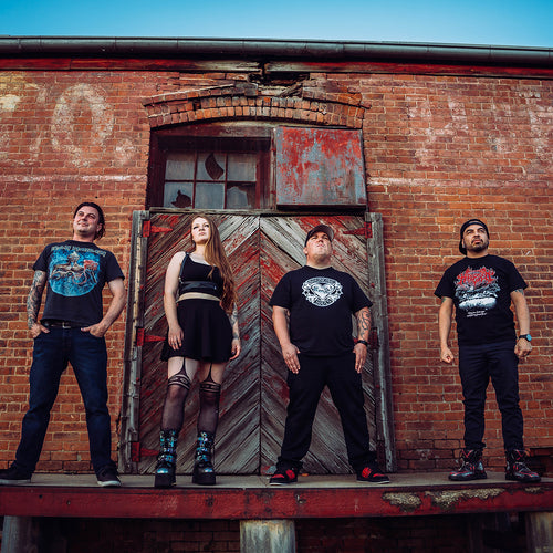 Four individuals standing in front of a brick wall with a wooden door.