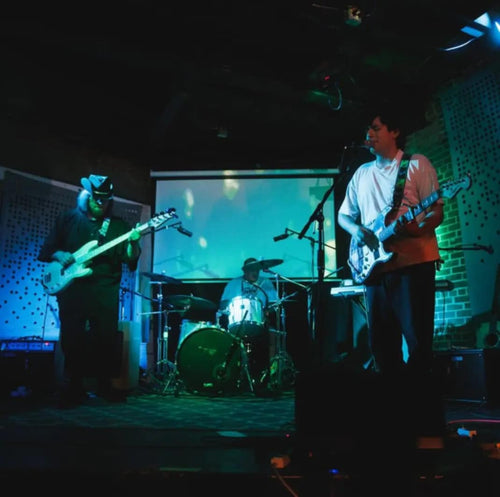 Image of Chodus - a new ONE on Stage band. Two people playing guitar and one person playing drums.