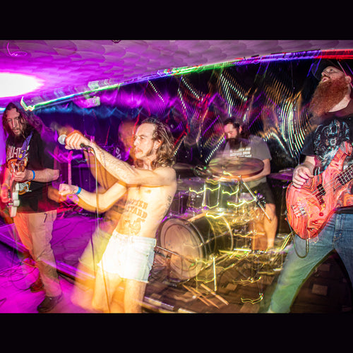 Band performing on stage with colorful lights and a drummer in the background