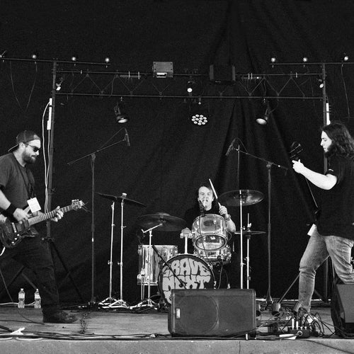 Band performing on stage with instruments and a microphone stand.