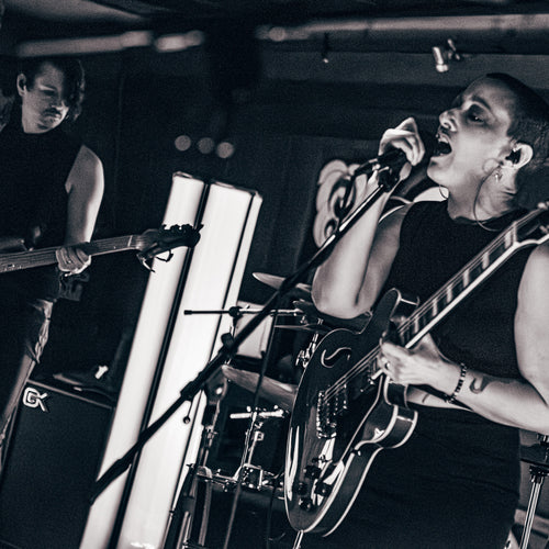 Black and white photo of a band performing on stage with instruments and a microphone.