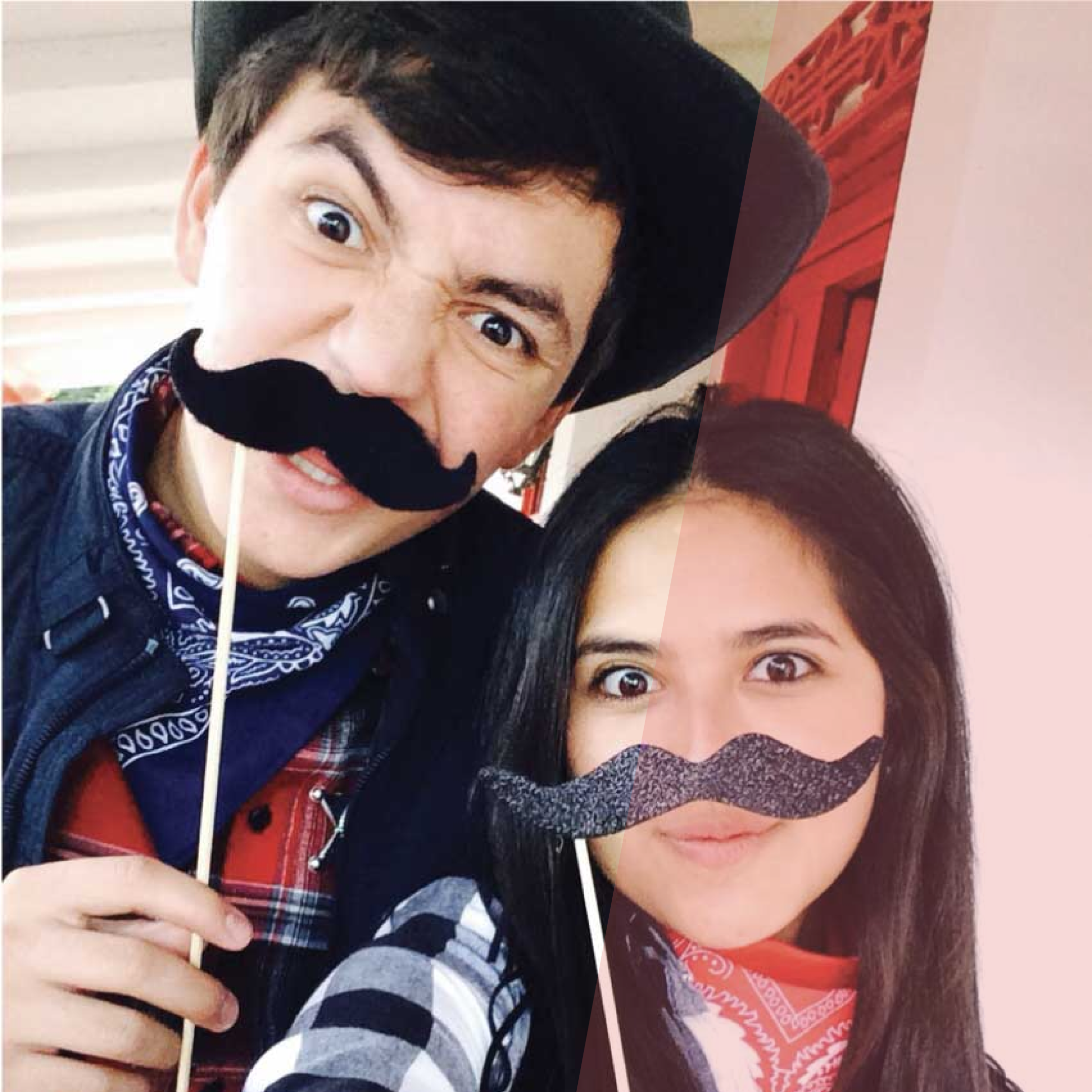 Two people posing for a photo with stick mustaches. 