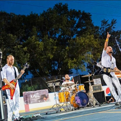 Image of SAHE - a ONE on Stage band. Two people playing guitar, one person playing drums. 