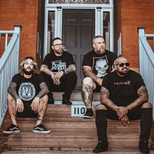 Image of Suicide Cages - a ONE on Stage band. Four people sitting on stairs leading up to a house. 