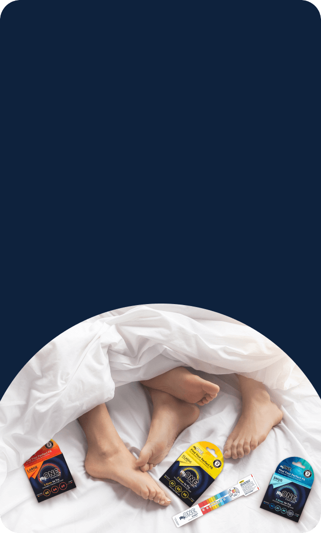 Person lying in bed with various products on the sheets