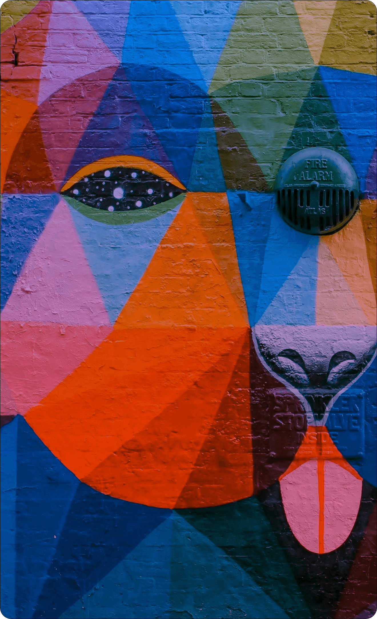Colorful abstract mural on a wall with geometric shapes and a bottle cap.