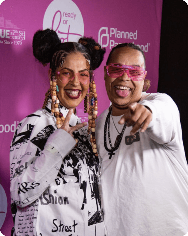Two people posing in front of a Planned Parenthood sign.